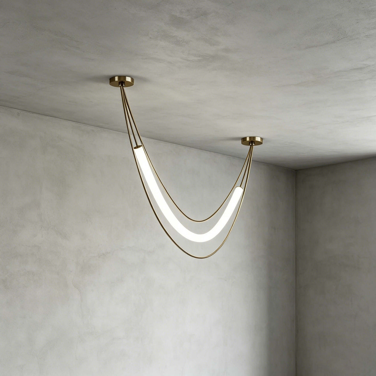 Compact gold Clérachic pendant with a lit white tube and fine gold cords, hung in a plaster-walled corner.