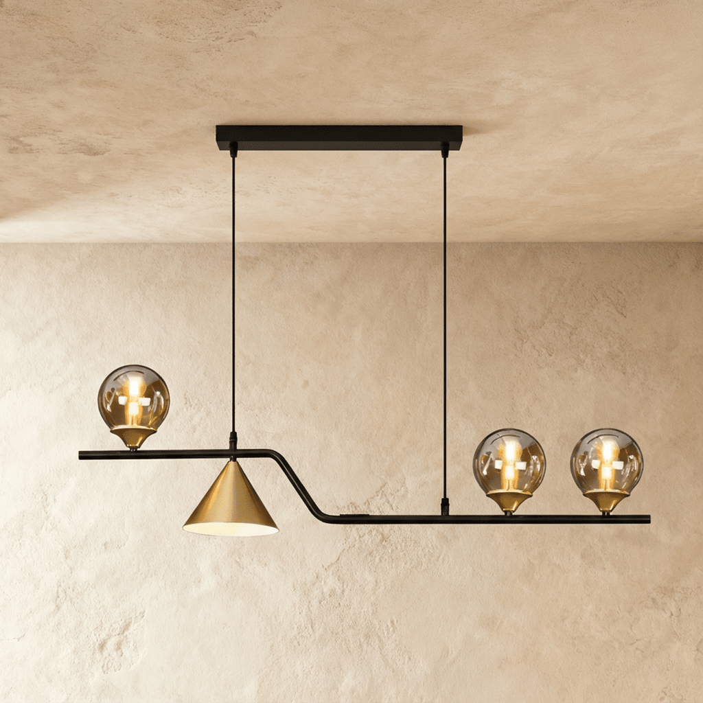 Clérachic linear pendant, a black bar with three glass globes and a gold cone shade, hung on two cords in a studio.