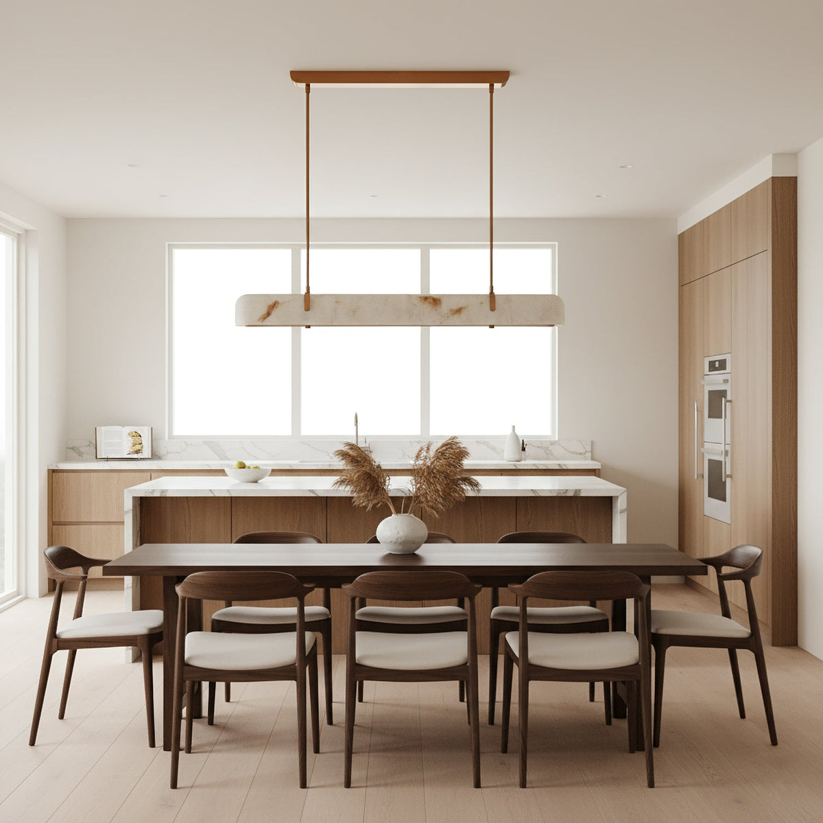 A slim Clérachic linear pendant hangs in front of a large window, above a dark dining table with wooden chairs.