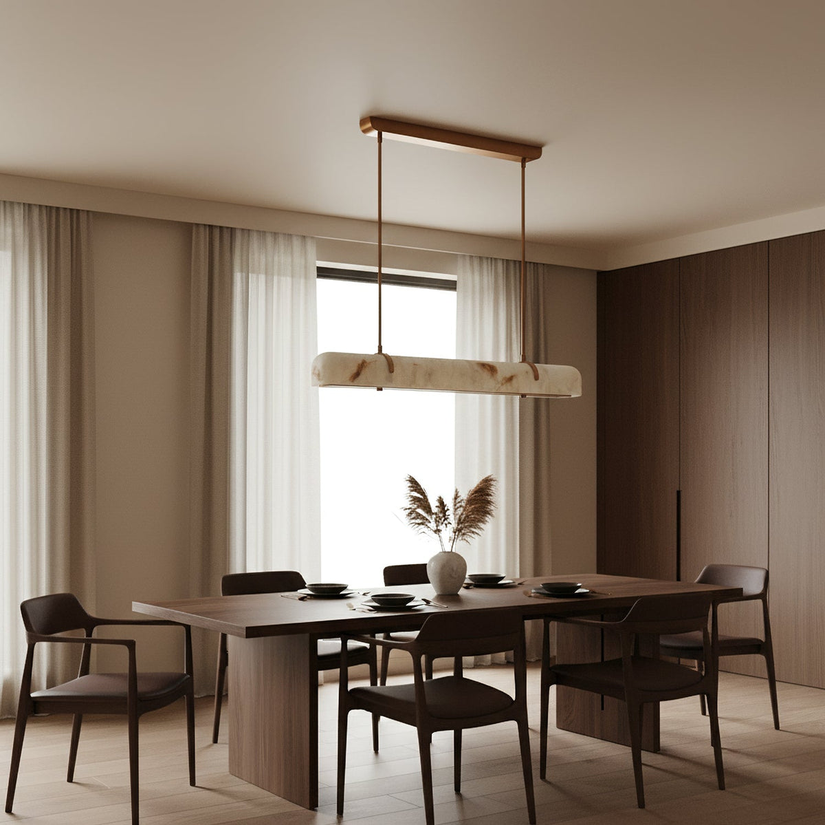 An unlit Clérachic linear pendant hangs in front of a window with sheer curtains, over a long table with dark chairs.