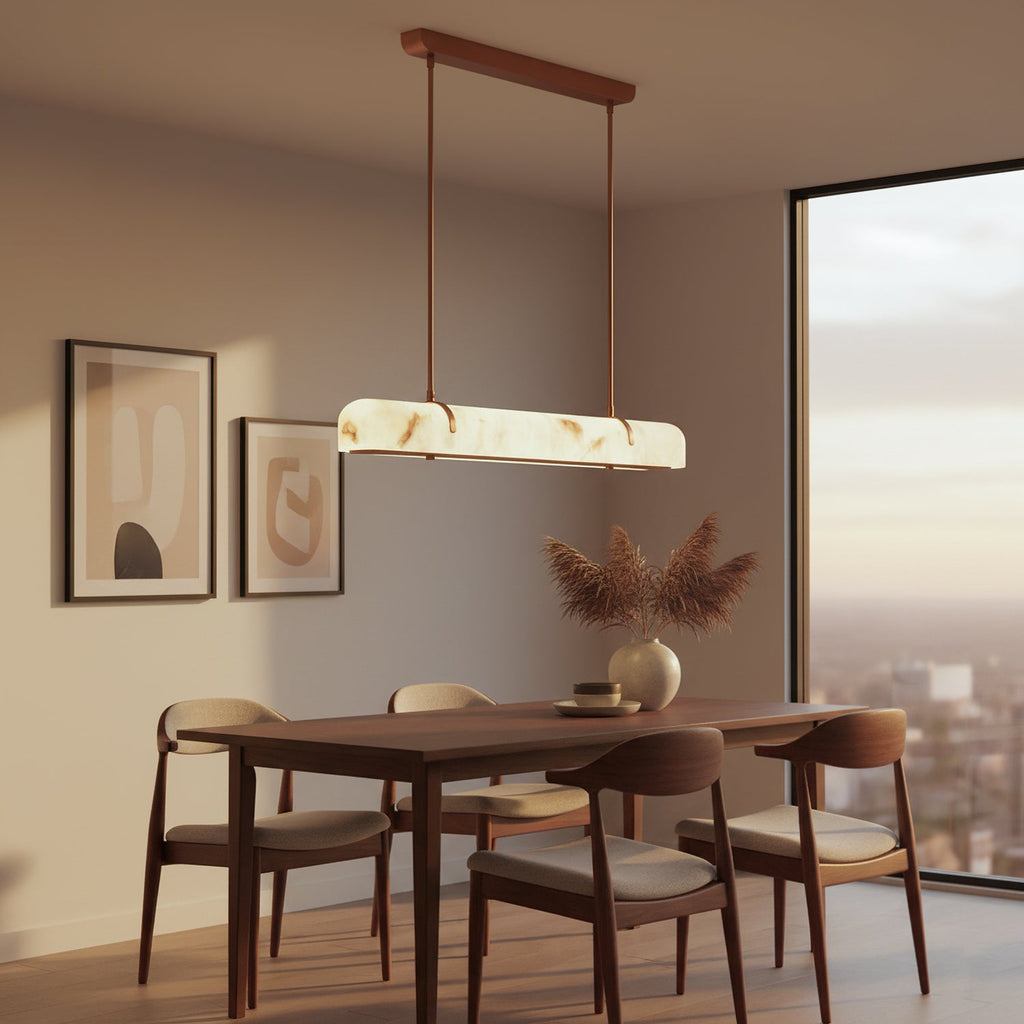 A Clérachic linear pendant glows above a wooden table with a dried-grass vase, with framed prints and a city view.