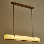 A lit Clérachic linear pendant seen from the end, its warm glow showing the stone-like veining.