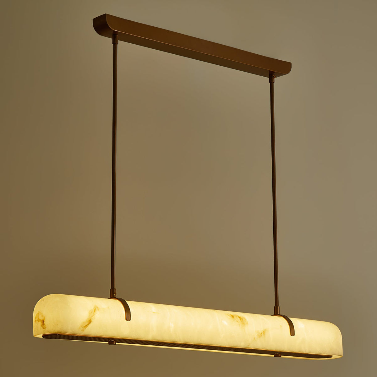 A lit Clérachic linear pendant seen from the end, its warm glow showing the stone-like veining.