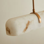 Close view of the rounded end of this Clérachic pendant's shade, with a curved copper-toned clip holding the rod.