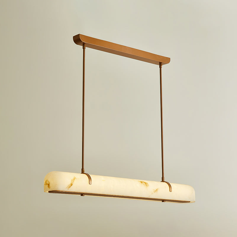 A Clérachic linear pendant glows on a warm beige backdrop, with the light showing through the shade.