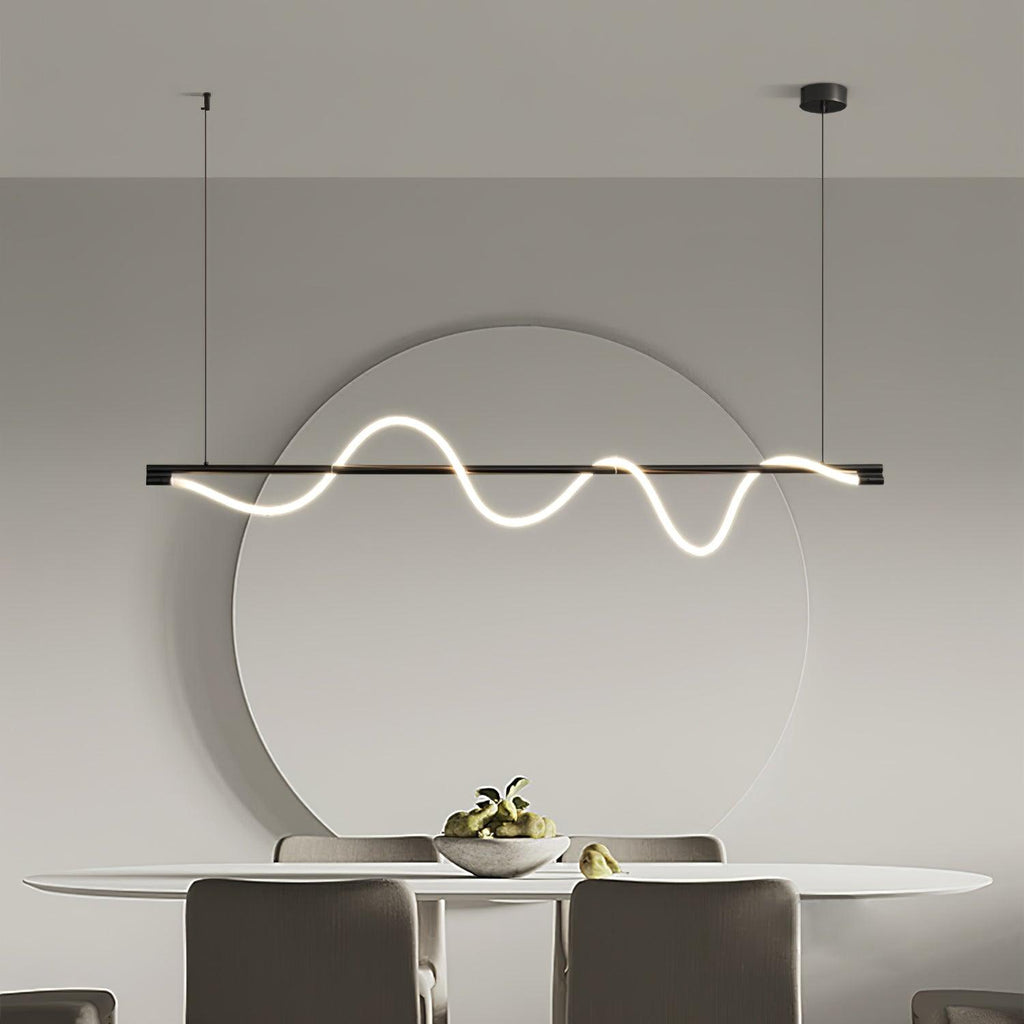 Black Clérachic linear pendant lit above an oval dining table, with a large round mirror on the grey wall behind.