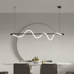 Black Clérachic linear pendant lit above an oval dining table, with a large round mirror on the grey wall behind.