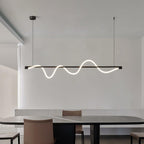 Clérachic linear pendant with a black bar and glowing white wave, over a dark table and tan leather chairs.