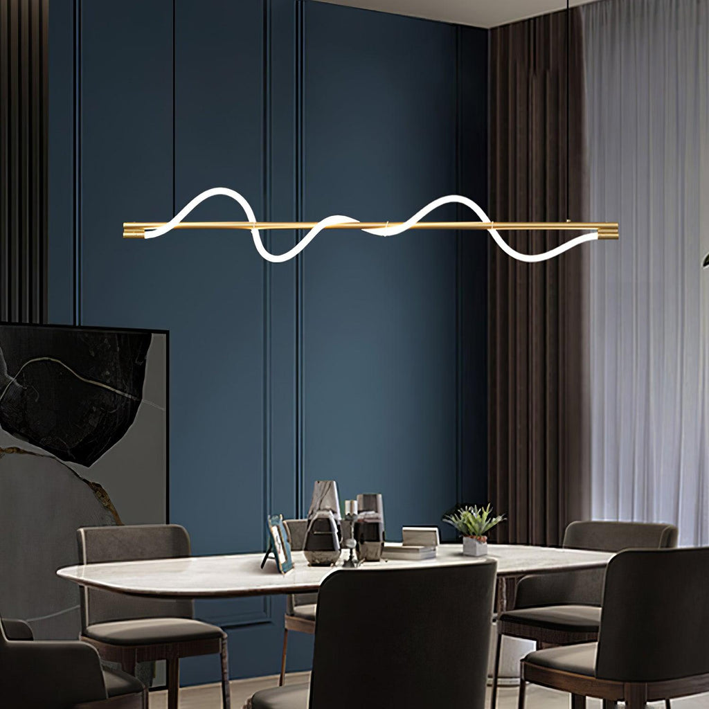 Brass Clérachic linear pendant lit above a marble-topped table, with a deep blue panelled wall behind.