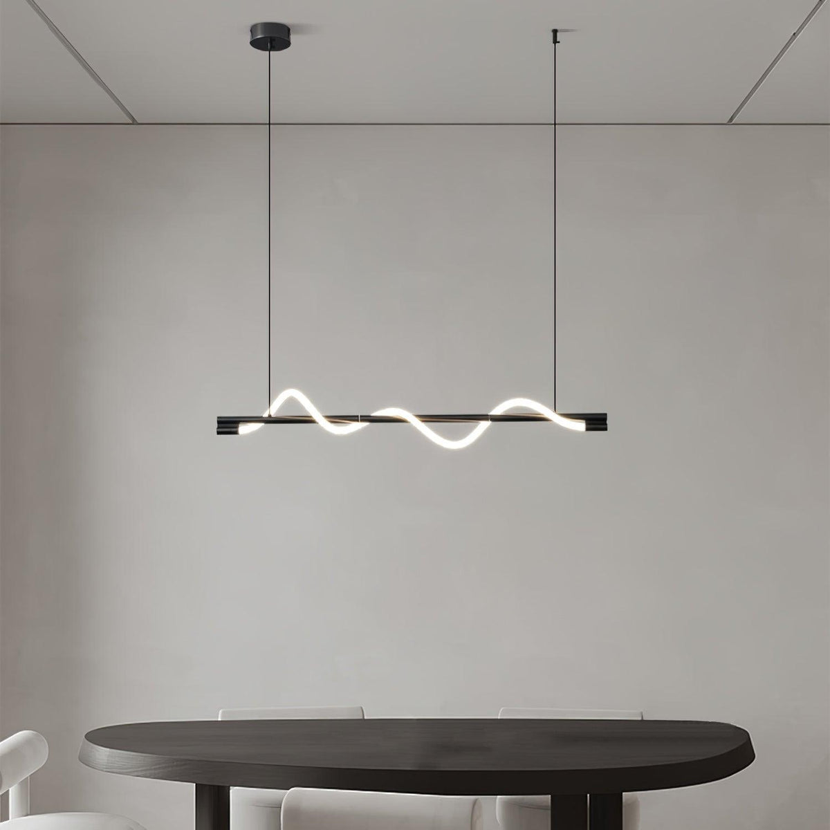 Clérachic black linear pendant with a low glowing wave over a rounded dark table, on a plain grey wall.