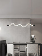 Black Clérachic linear pendant over a dark table with pale upholstered chairs, in a calm grey room.