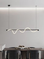 Clérachic black linear pendant seen against a cove-lit wall, over a table with a bowl of nuts and dark chairs.