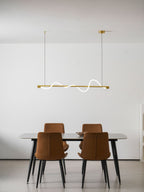 Clérachic brass linear pendant with a thin white line, hung high over a table with four rust-coloured chairs.