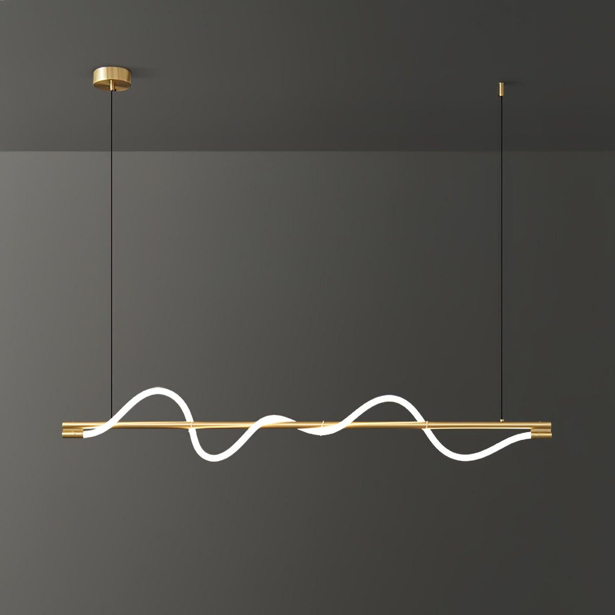 Brass Clérachic linear pendant lit with a deep wave, on a brass canopy against a dark grey wall.
