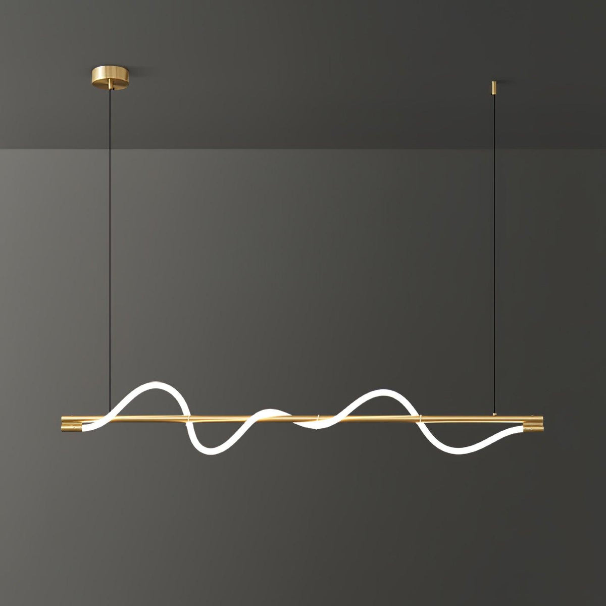 Brass Clérachic linear pendant with a bright wave and a brass canopy, in front of a dark grey wall.
