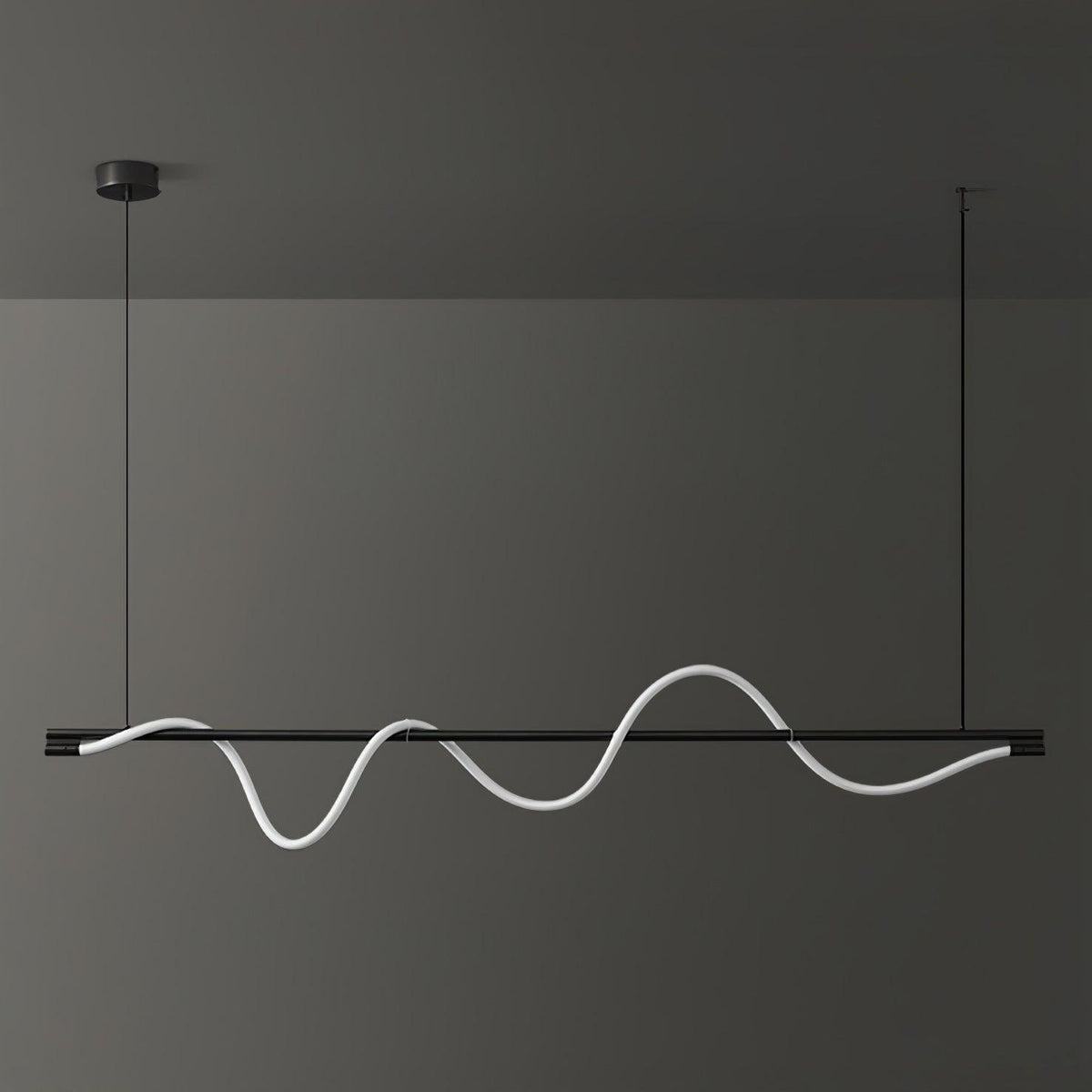 Wide black Clérachic linear pendant with an unlit white silicone wave, against a dark grey wall.