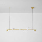 Unlit brass Clérachic linear pendant with a white silicone wave, on a white wall with brass canopies.