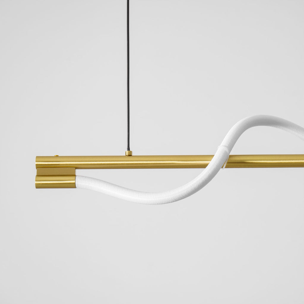Close view of the white silicone line leaving the brass end cap of this Clérachic linear pendant.