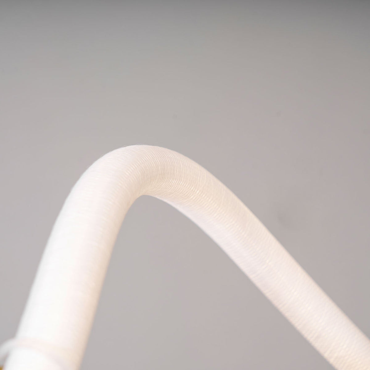 Close view of the soft, fine-textured white silicone line curving on this Clérachic linear pendant.