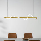 Brass Clérachic linear pendant with a lit wave, above two rust leather chairs and a wooden bowl.