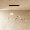 Clérachic 120 cm black pendant with a lit moon globe and a glowing LED line curving like a mountain ridge, on limewash.