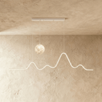 Clérachic 120 cm white pendant with a softly lit moon globe and a glowing mountain-ridge LED line, hung against limewash.
