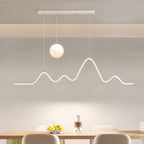 Clérachic 120 cm white pendant with a moon globe and mountain-ridge LED line hung above a pale wooden dining table with a fruit bowl.