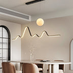 Clérachic 120 cm black mountain-ridge LED pendant with a glowing moon globe above an oval dining table by an arched window.