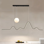 Clérachic 120 cm black pendant with a bright moon globe and a glowing LED line shaped like peaks, over a white counter and fruit.