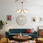 A red Clérachic globe chandelier hung in a living room with a teal sofa, a round mirror and a wooden coffee table.