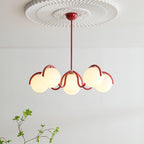 Clérachic red-framed chandelier lit beneath a white ceiling rose, with six glass globes on wavy arms and a green sprig below.