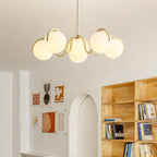 Creamy yellow Clérachic chandelier glowing in a bright room with an arched doorway and a wooden bookcase.