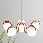 Close view of the red curving arms and rounded white globes on this Clérachic chandelier, with a green sprig at the lower left.