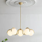 Creamy yellow Clérachic chandelier hanging below a plaster ceiling rose, its six glass globes lit warm.