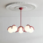 A red Clérachic chandelier with six glass globes hung from a white pleated ceiling rose against a pale wall.