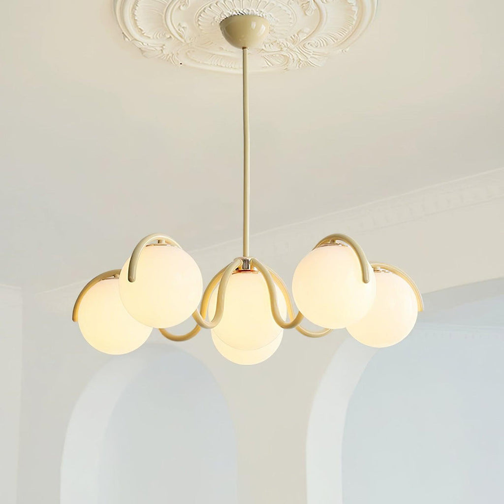 Clérachic creamy yellow chandelier lit in front of two white arched alcoves, below a plaster ceiling rose.