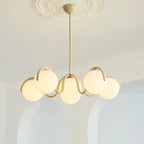 Clérachic creamy yellow chandelier lit in front of two white arched alcoves, below a plaster ceiling rose.