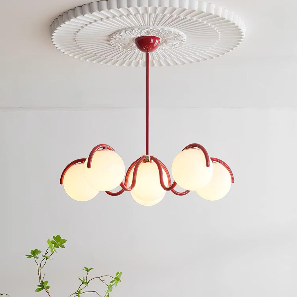 Red Clérachic chandelier lit beneath a pleated ceiling rose, with a green sprig in the lower left.