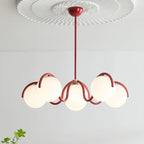 Red Clérachic chandelier under a white ceiling rose, with six glass globes lit and a green sprig at the lower right.