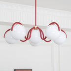A red Clérachic chandelier seen from below against a white panelled wall, with a coved ceiling edge above.