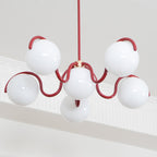 Looking up at this red Clérachic chandelier, with its six white globes lit and a coved ceiling edge behind.