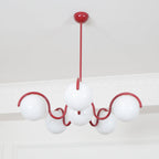 A red Clérachic chandelier with unlit white globes, seen from below against a white cornice and pale wall.