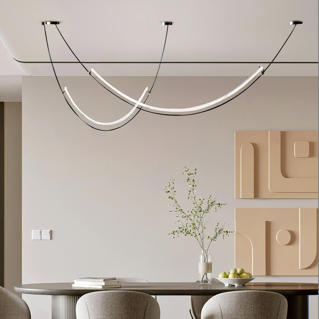 This Clérachic pendant lit above a round dining table, two crossing curves of white light under a ceiling set with peach relief panels.