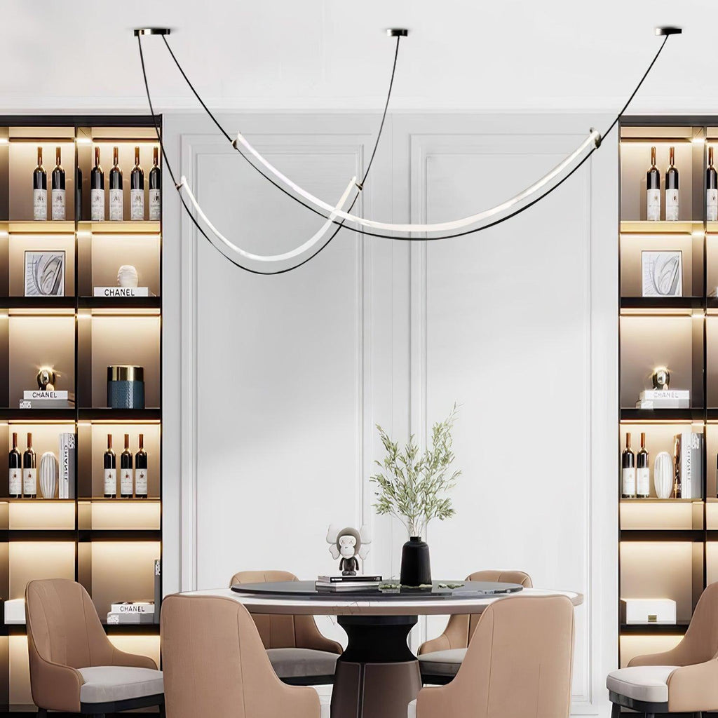 Clérachic pendant hung in front of a white panelled wall between two lit shelving units of bottles, over a round dining table.