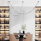 Clérachic pendant hung in front of a white panelled wall between two lit shelving units of bottles, over a round dining table.
