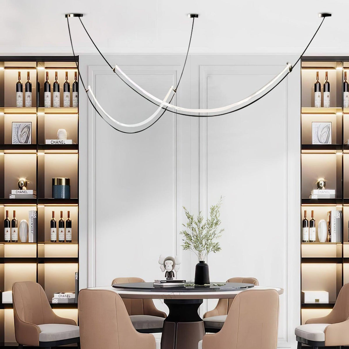 Clérachic pendant hung in front of a white panelled wall between two lit shelving units of bottles, over a round dining table.