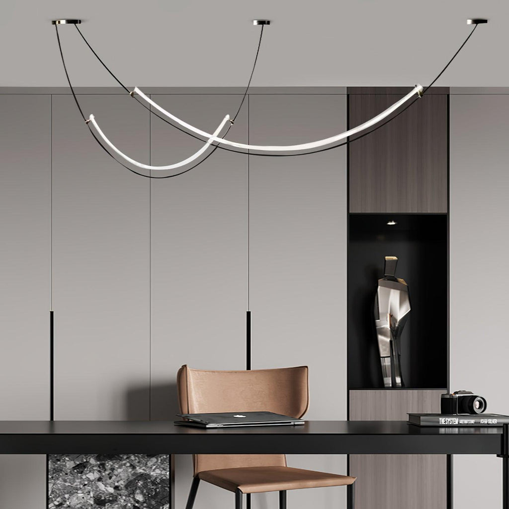 Lit Clérachic pendant in a grey room above a dark desk and tan leather chair, with a recessed niche and a small camera on the shelf.