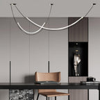 Lit Clérachic pendant in a grey room above a dark desk and tan leather chair, with a recessed niche and a small camera on the shelf.