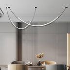 Two staggered curves of this Clérachic pendant glowing above a dining table, in front of grey fluted wall panelling.