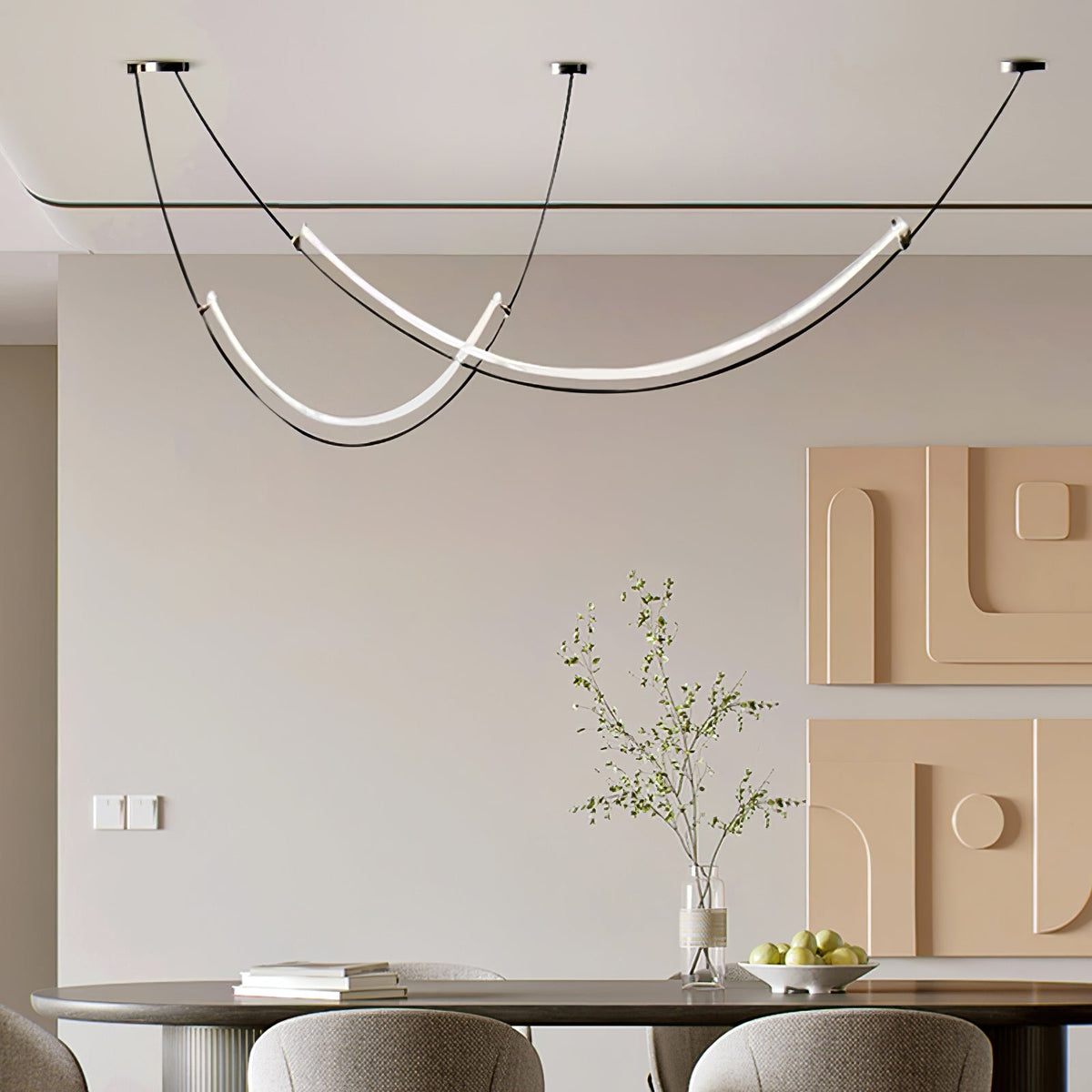 Clérachic pendant above an oval dining table with a fruit bowl and sprigs in a vase, in front of two peach wall reliefs.